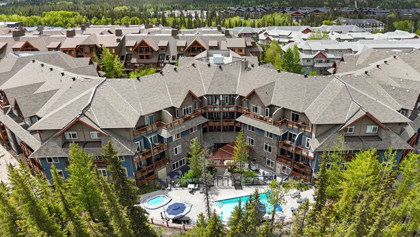 A resort with multiple buildings, a swimming pool, and mountains in the background.
