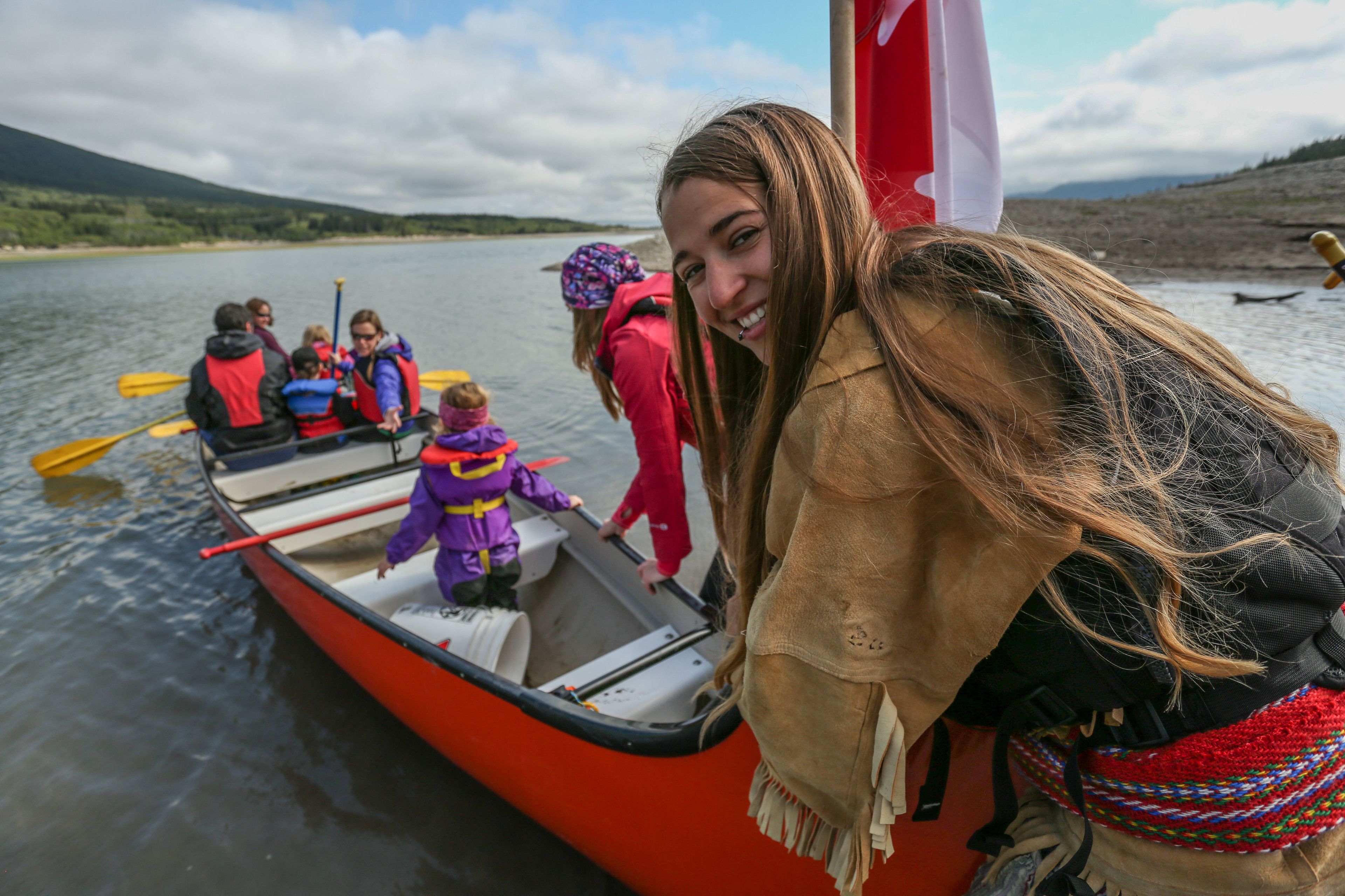 A group of people in a boat on a lake with a mountainous backdrop.