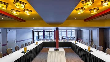Un salón de conferencias con una larga mesa, sillas y un amplio ventanal.