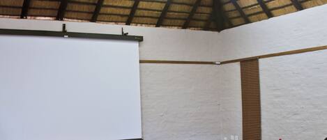 A conference room with a long table, chairs, a projector screen, and water bottles.