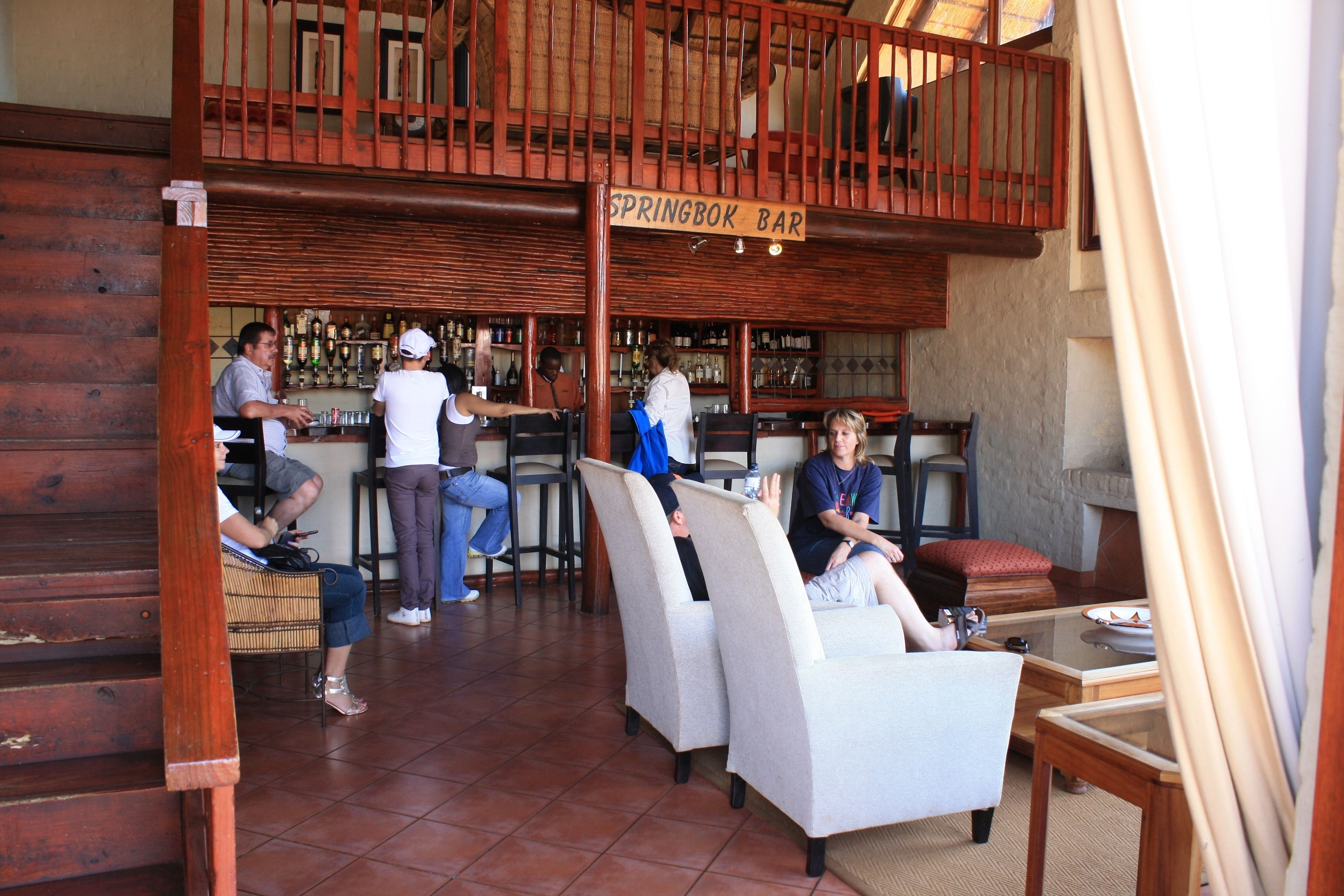 A bar area with a sign reading "SPRINGBOK BAR," wooden furniture, and a tiled floor.