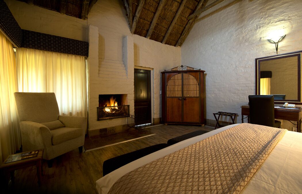 A cozy room with a fireplace, a bed, a chair, and a desk.