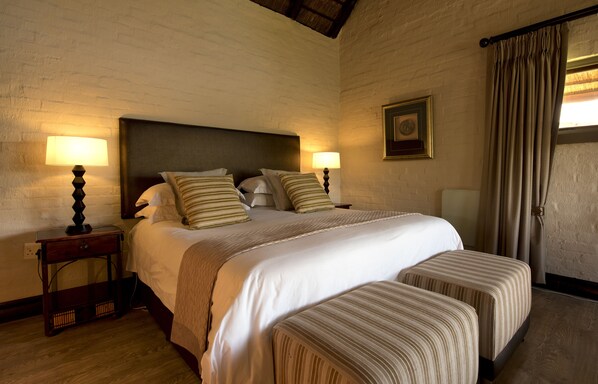 A double bed with a headboard, two bedside tables with lamps, and a window with curtains.