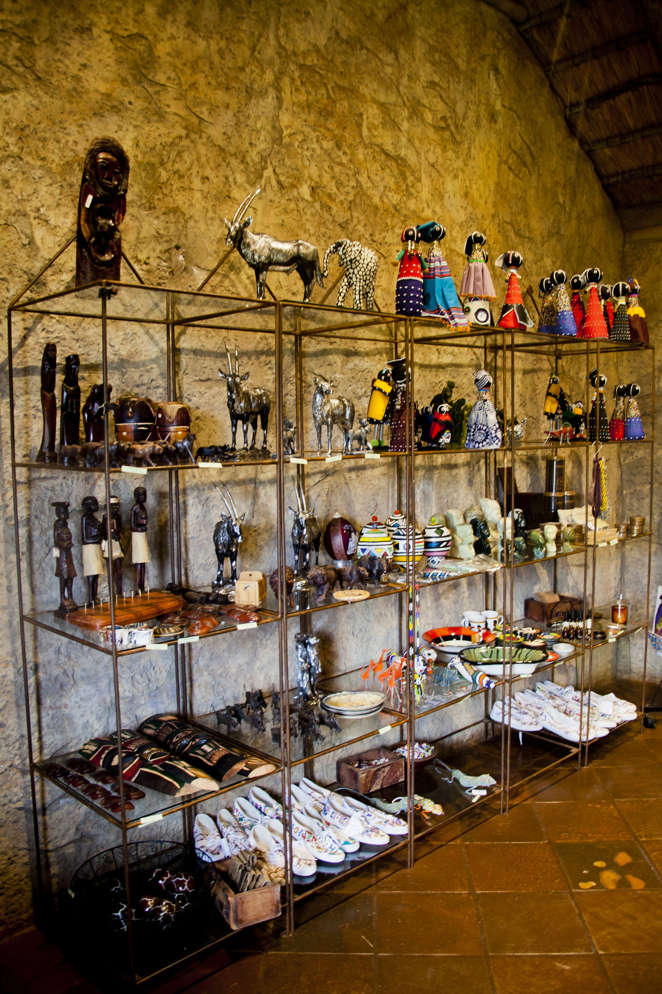 Une exposition de divers objets d’art et d’artisanat, ainsi que de chaussures traditionnelles, présentés sur des étagères.