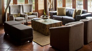 A spacious living room with a high ceiling, large windows, and a view of the outdoors. - Entabeni Mountain Lodges (Mookgopong)