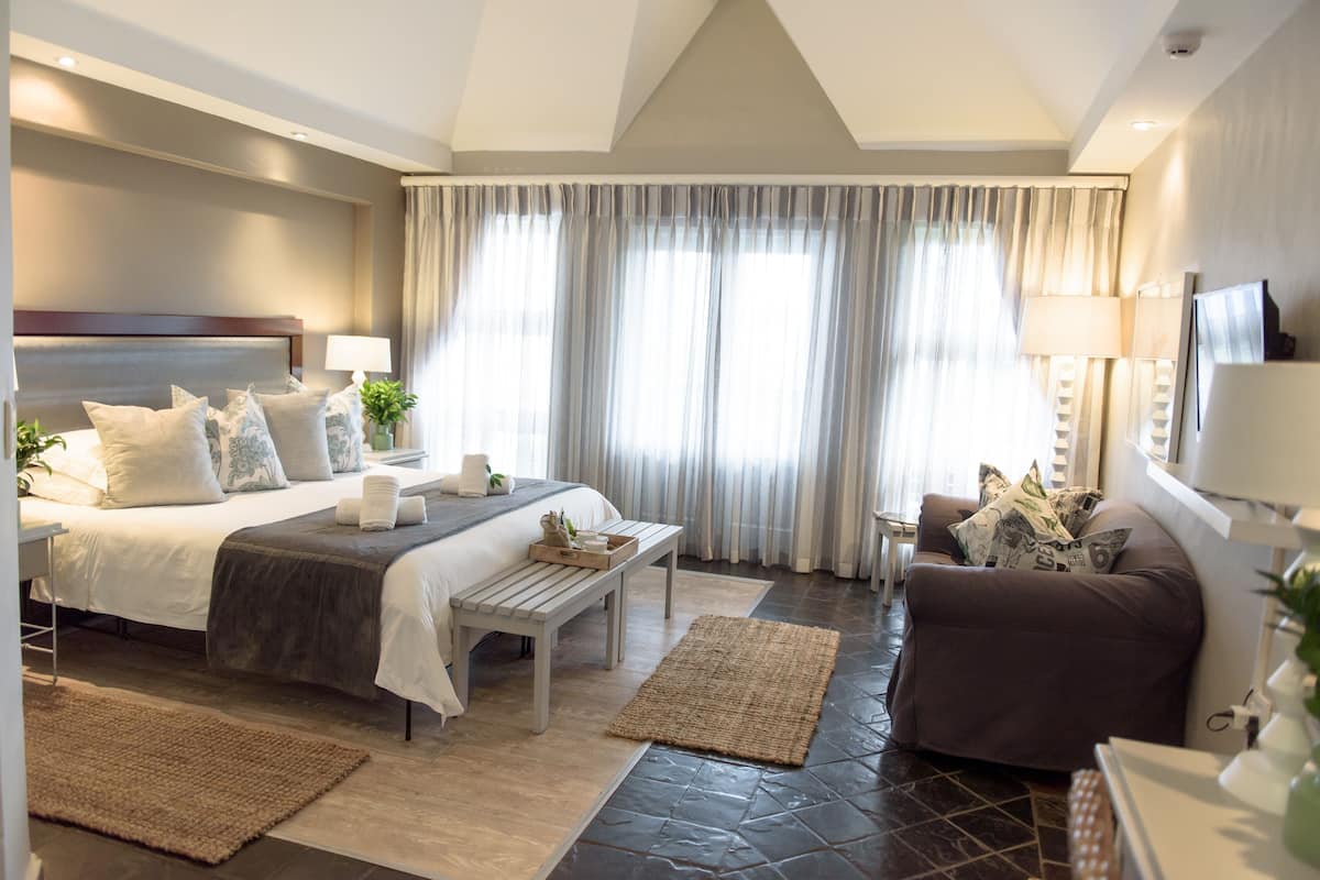 A modern hotel room with a large bed, a sofa, a small table, and a TV.