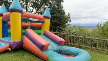 Kids can play on the inflatable play structure with multiple slides and a central platform surrounded by a designated play area.