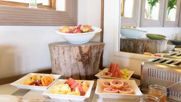 Un bufé de desayuno con diversas frutas y un tostador.