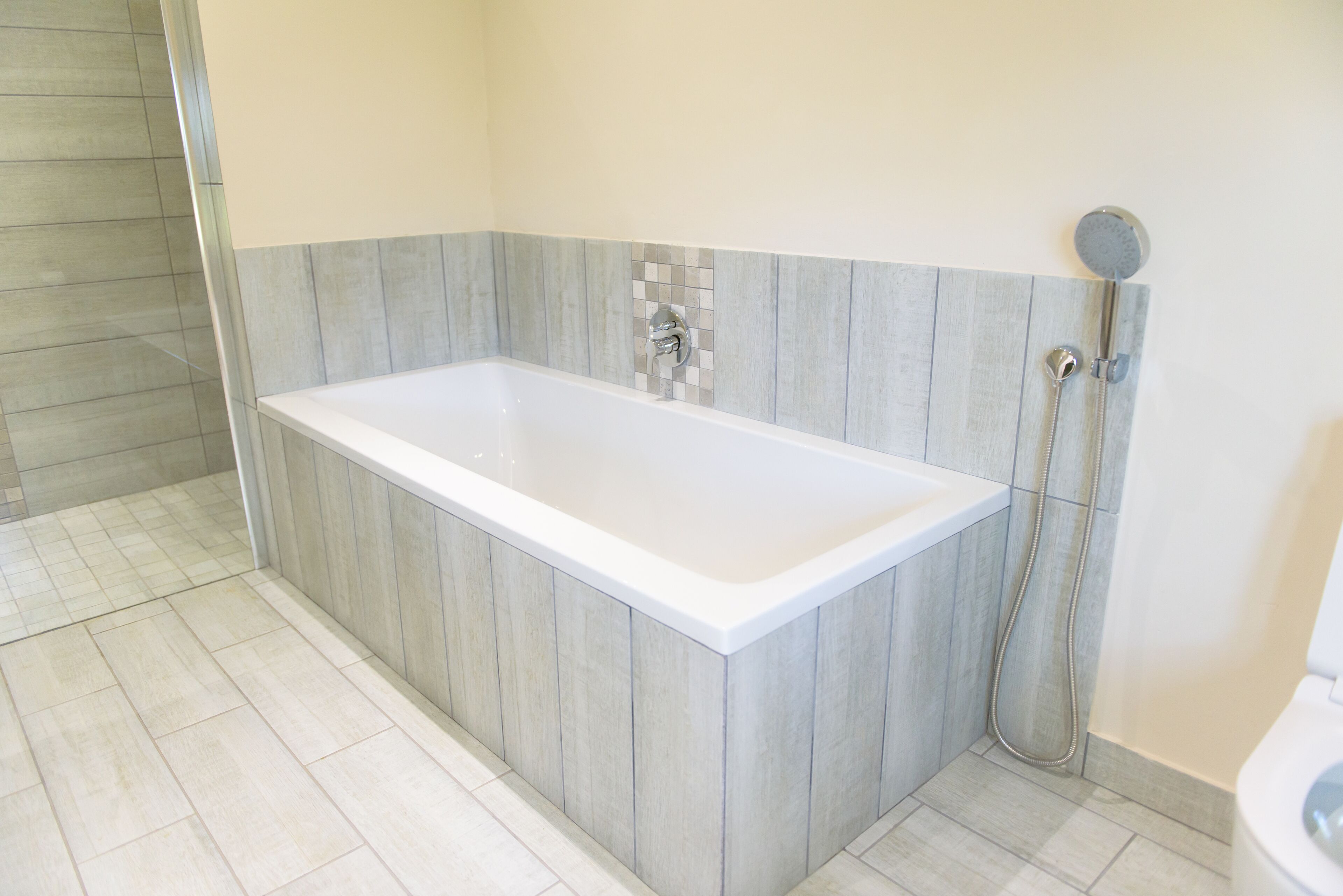 Un baño moderno con una bañera rectangular, un cabezal de ducha y un inodoro.