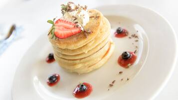 A stack of pancakes with strawberries and blueberries on a white plate.