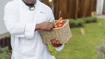 Eine Person in einem weißen Kochschürze hält einen Korbkorb mit Karotten und Lavendel.