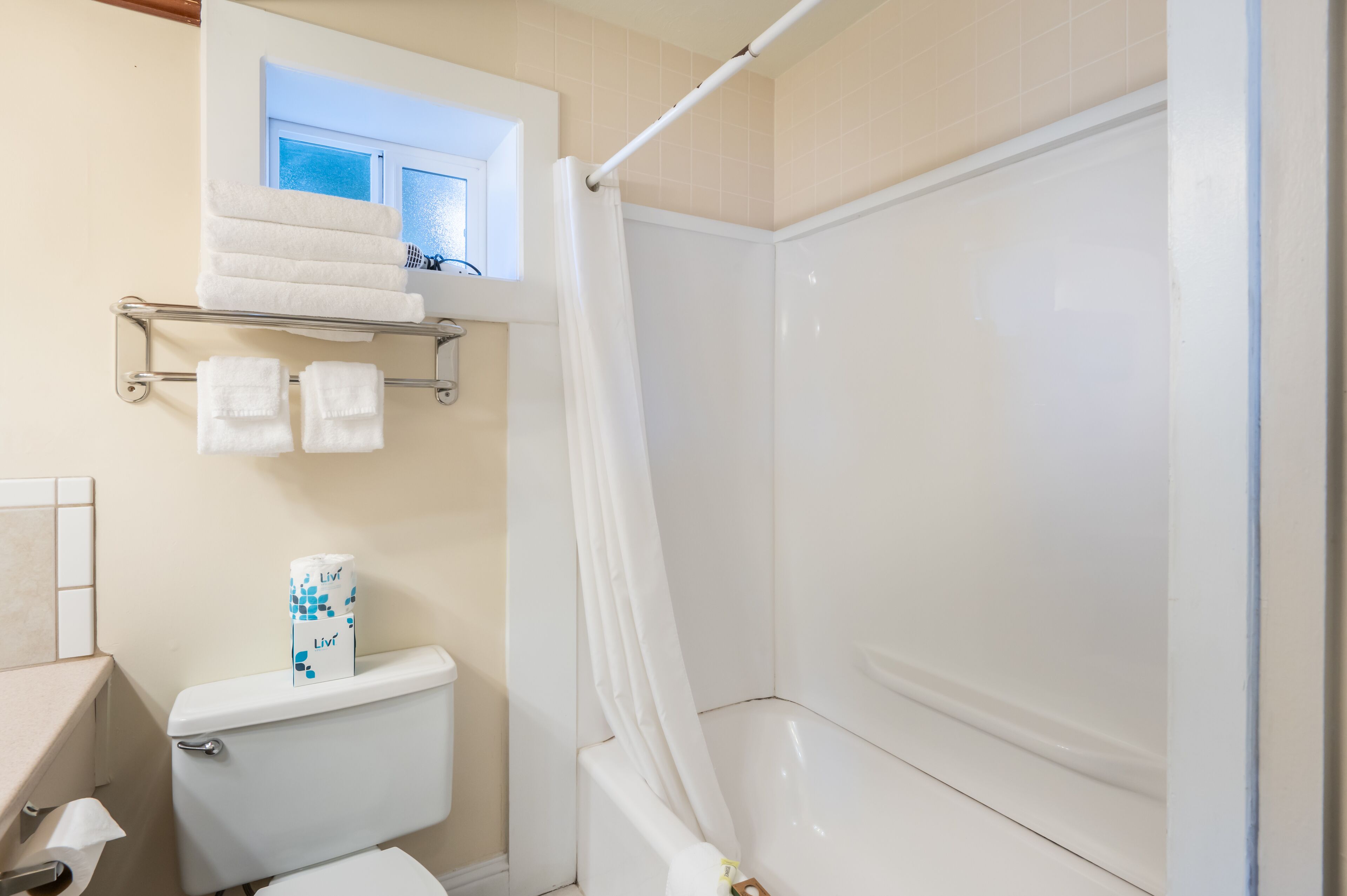 Un baño con inodoro, ducha, ventana y toallero.