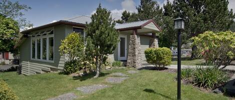 A house with a stone chimney, a stone porch, and a well-maintained lawn with a stone pathway.
