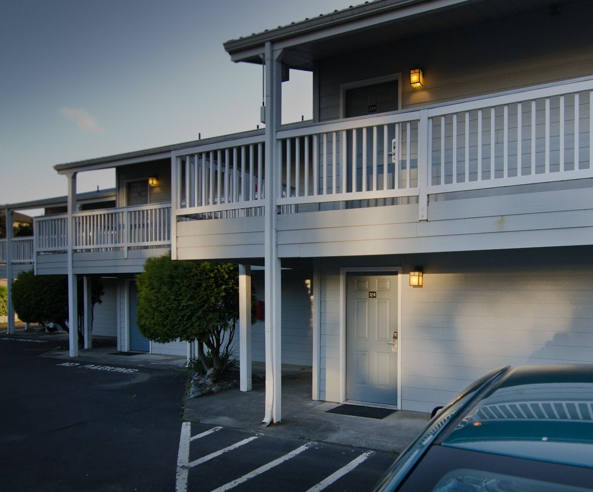 A motel with two-story buildings, each with a balcony and a single door.