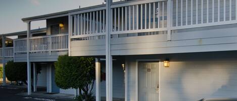 A motel with two-story buildings, each with a balcony and a single door.