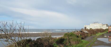 A coastal view with a beach, a path, and a building with a sign.