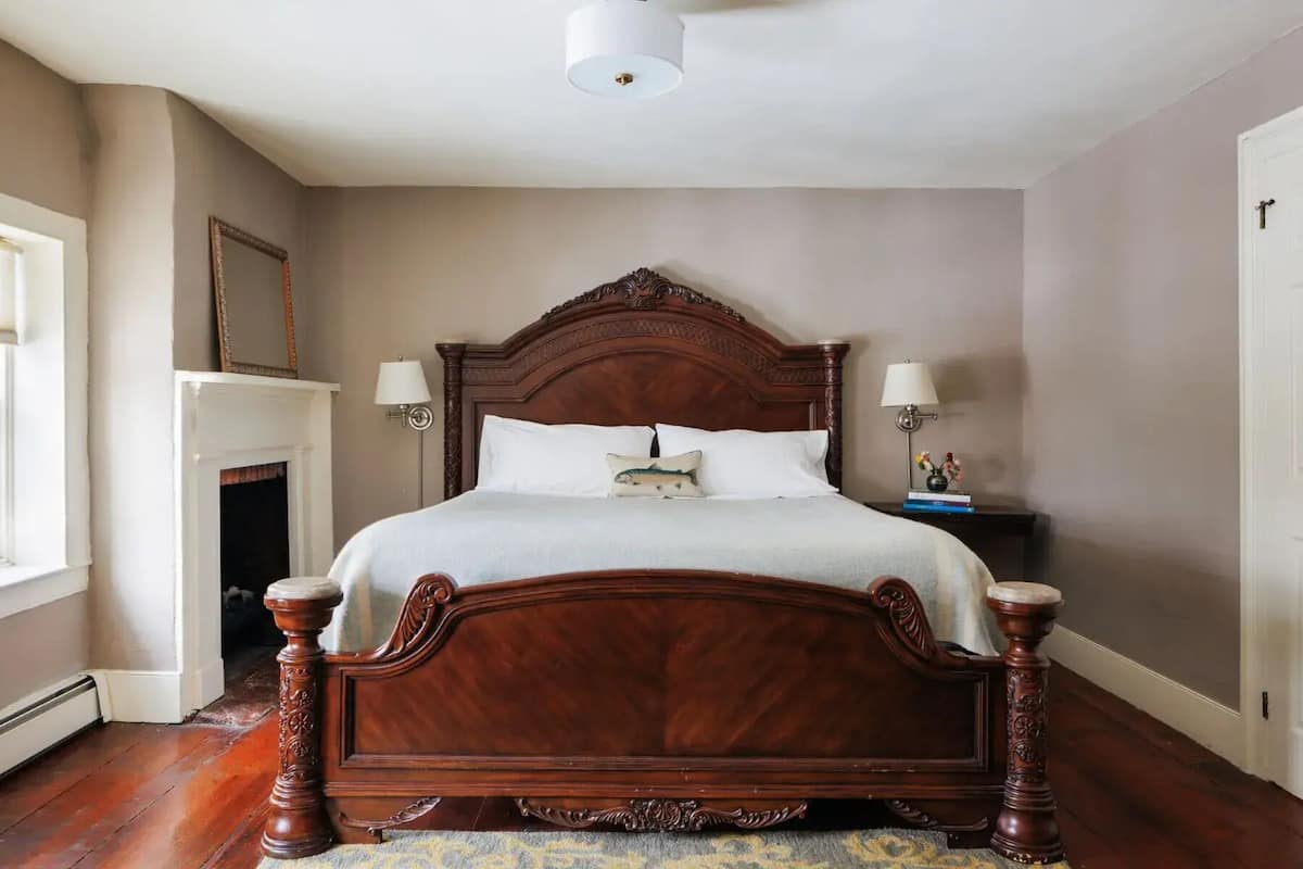 A large, ornate wooden bed with a high headboard, two bedside lamps, and a decorative pillow.