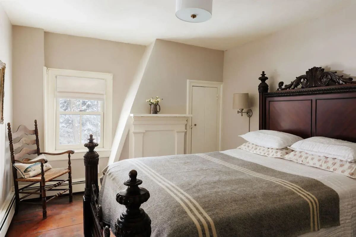 A bedroom with a large bed, a chair, a dresser, and a window with a view.