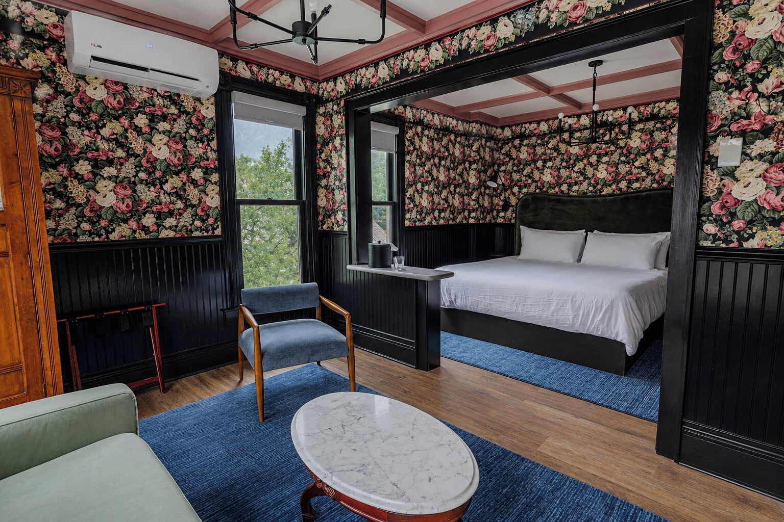 Ein Schlafzimmer mit Bett, Stuhl, Tisch und Fenster.