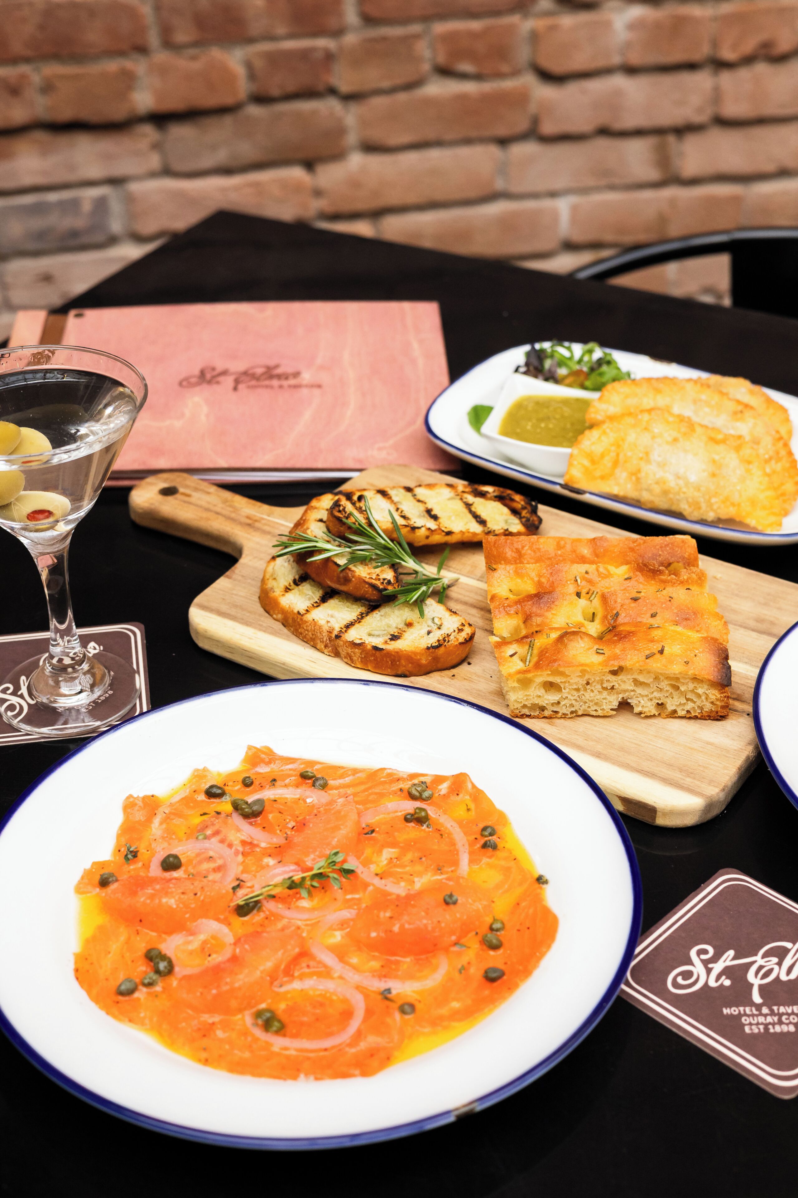 A table with a variety of dishes including a plate of pasta, grilled bread, and a dessert.