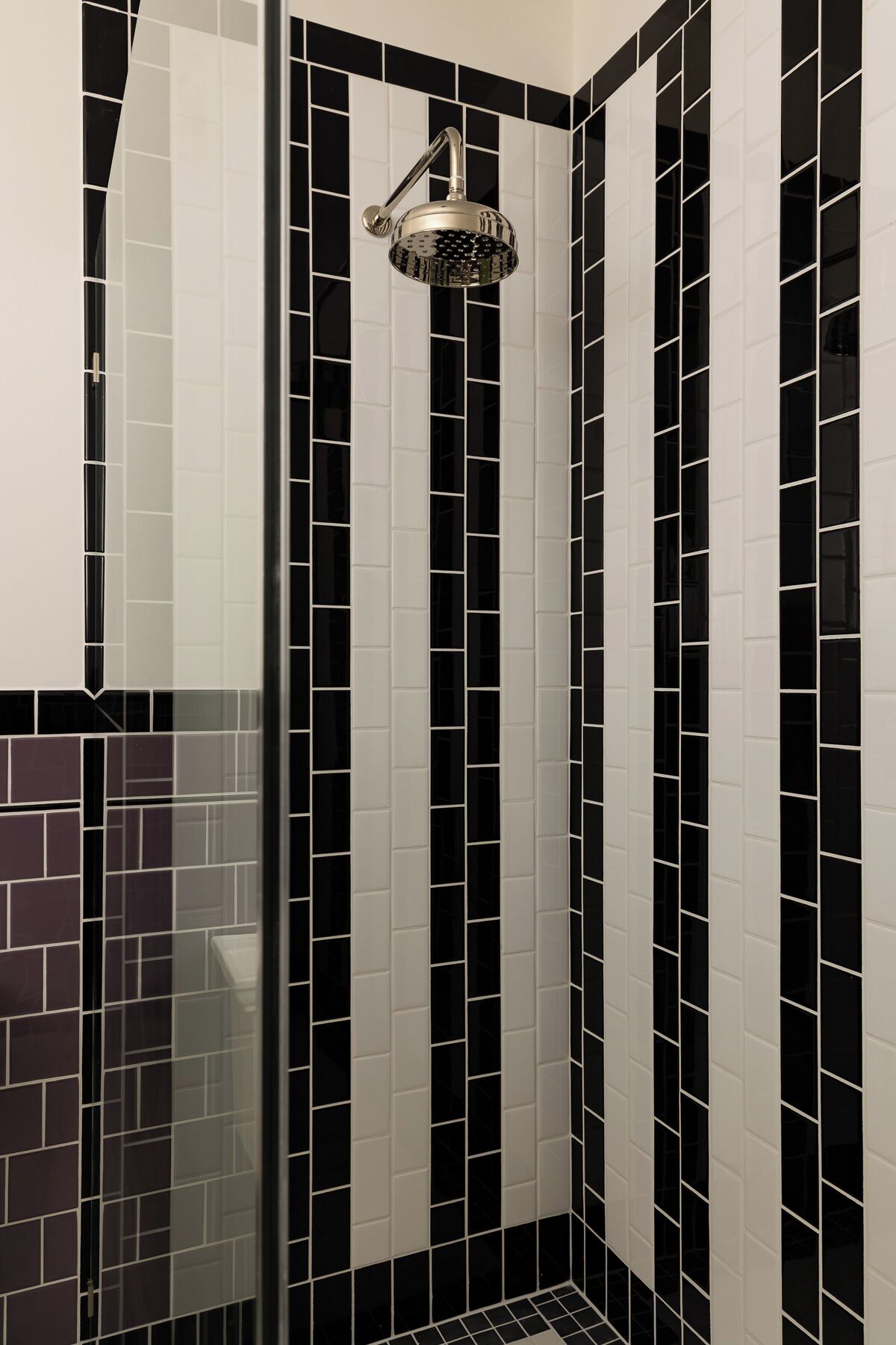 Ducha con cabezal cromado y pared con diseño blanco y negro.