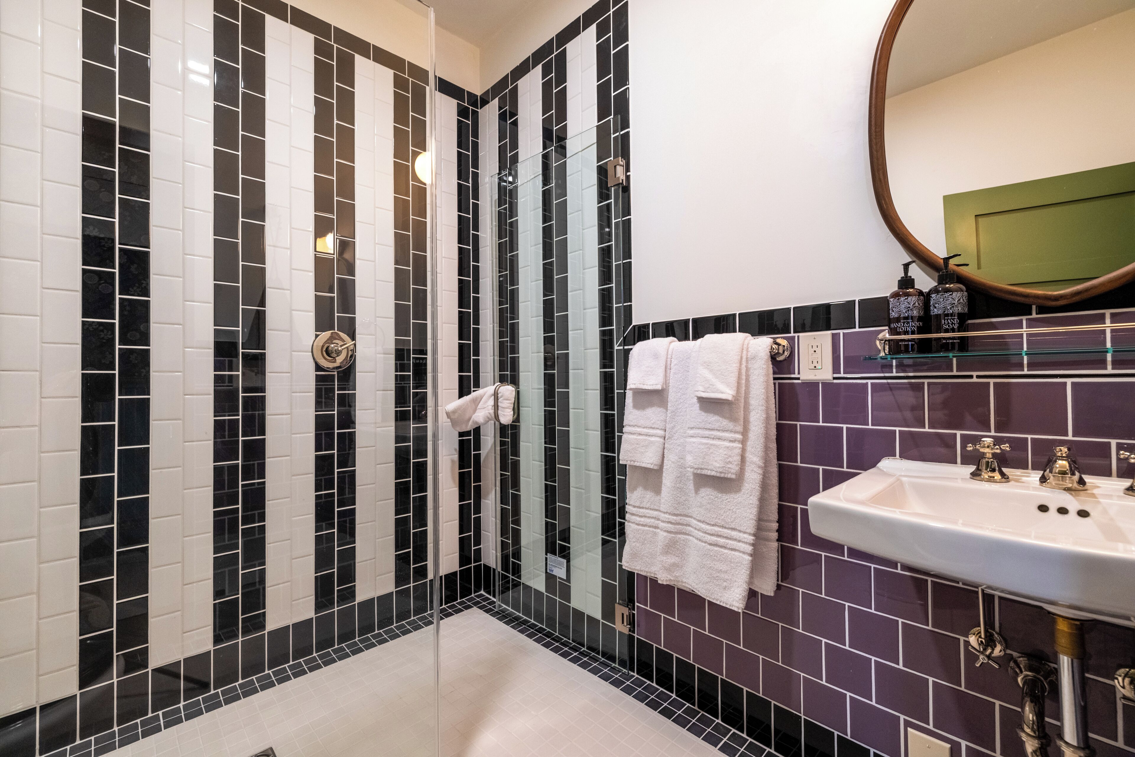 Un baño con ducha de mampara de vidrio, un lavabo blanco con detalles dorados y un espejo sobre el lavabo.