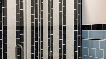 A shower with a glass door and a handheld showerhead.