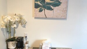 A kitchen counter with a coffee maker, a potted plant, and a sign.