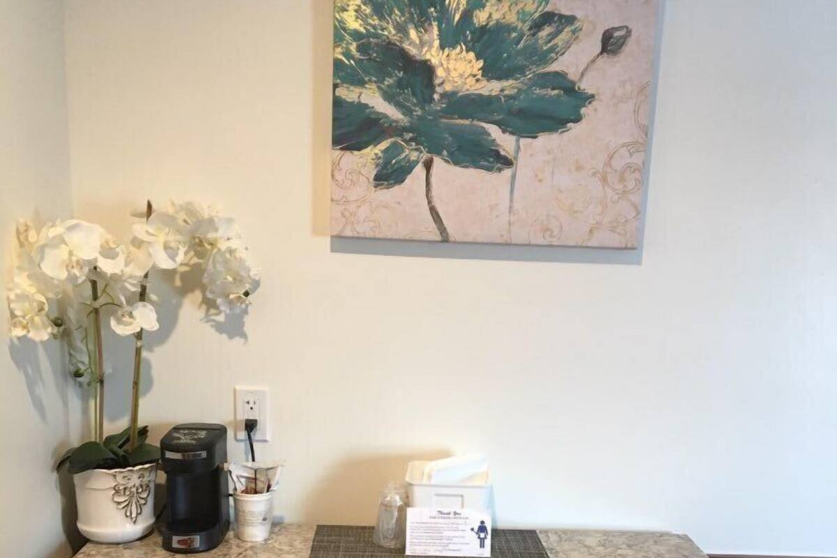 Un comptoir de cuisine avec une machine à café, une plante en pot et un panneau.