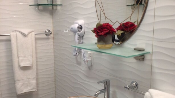 A modern bathroom with a white sink, a large mirror, and a towel rack.