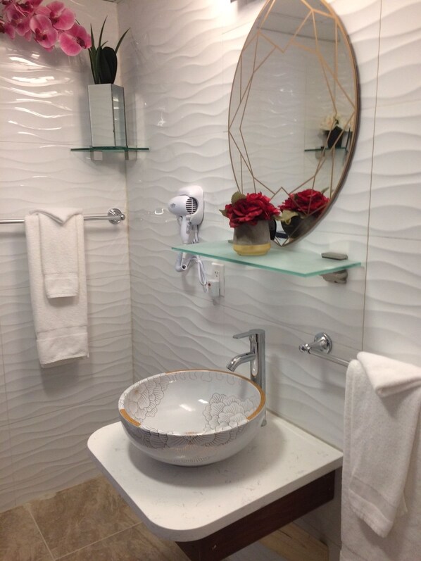 A modern bathroom with a white sink, a large mirror, and a towel rack.