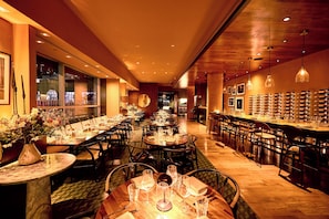 A restaurant with multiple dining tables, chairs, and a bar area.
