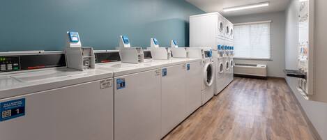 A laundry facility with multiple washing machines and dryers, a digital scale, and a QR code for self-service.