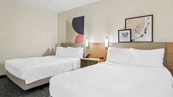 A hotel room with two beds, a nightstand, a phone, and two wall-mounted lamps.