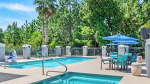 Piscina com escada de metal, cercada por uma cerca e árvores.