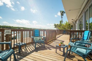 A wooden deck with blue chairs and a table, overlooking a body of water.