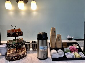 Preparación para el desayuno con avena Quaker, una almohadilla térmica, vasos desechables y una variedad de alimentos para el desayuno.
