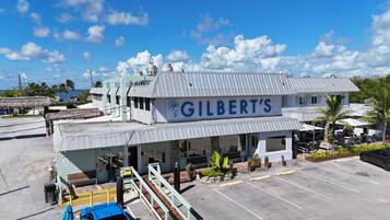 A building with a sign reading "GILBERT'S" and a covered outdoor seating area with plants.