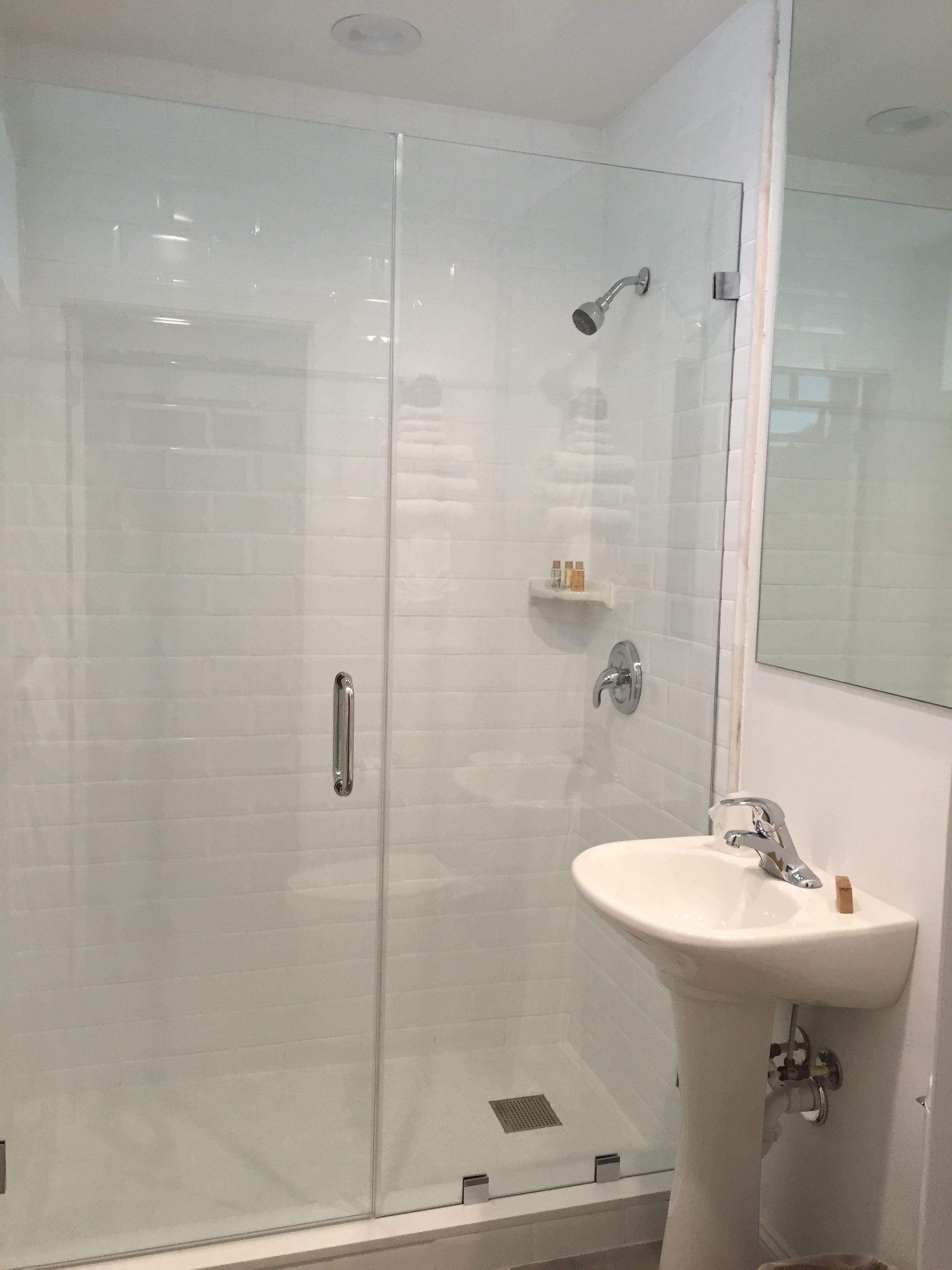 Une salle de bain avec une douche à parois de verre, un lavabo blanc et un miroir.
