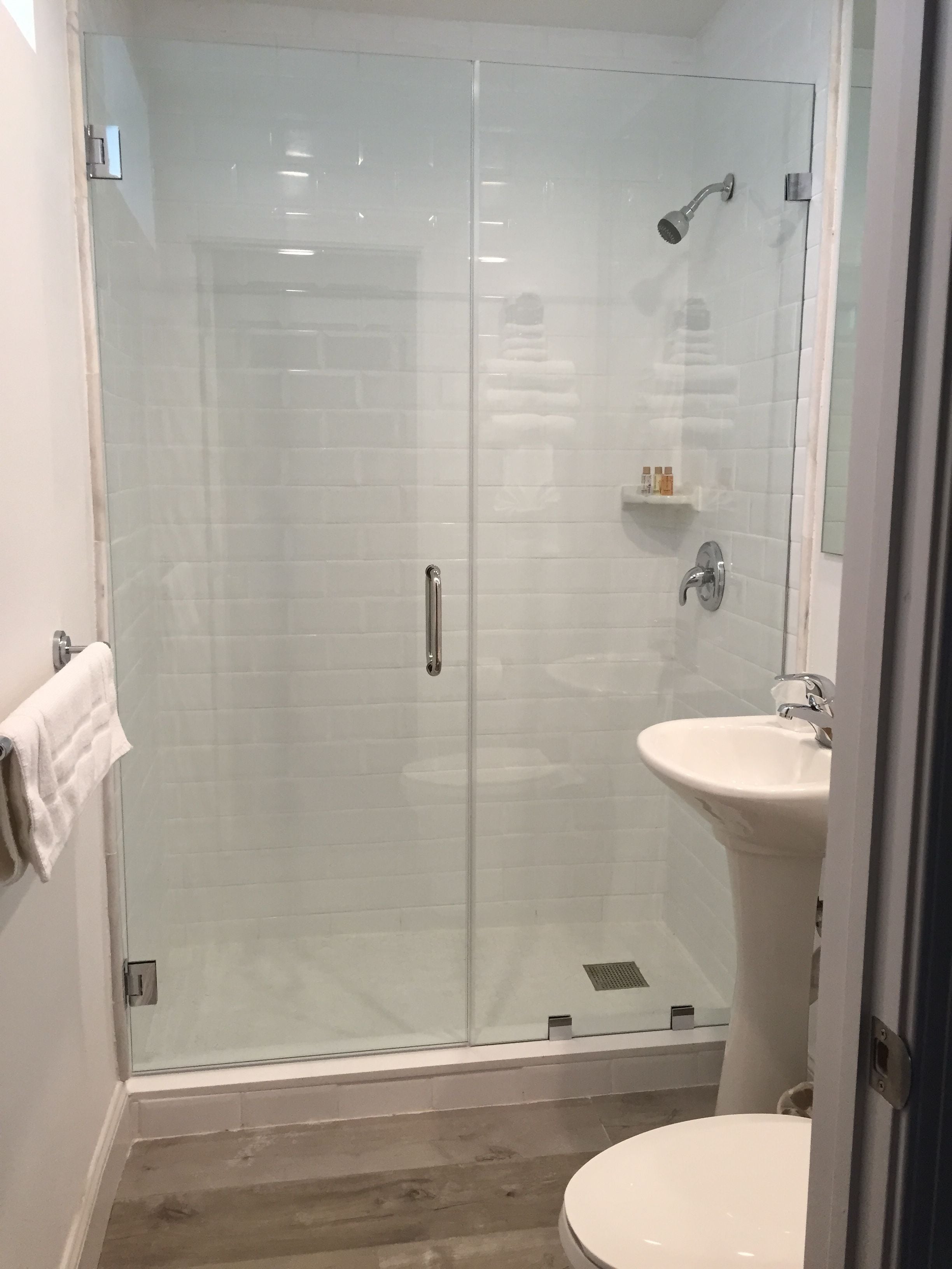 A modern bathroom with a glass-enclosed shower, a pedestal sink, and a toilet.