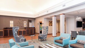 A spacious lobby with a reception desk, seating area with armchairs, a coffee table, and a television mounted on the wall. - Residence Inn Marriott Moline (Moline)