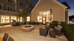 A hotel courtyard with outdoor seating, a fire pit, and a well-lit entrance. - Residence Inn Marriott Moline (Moline)