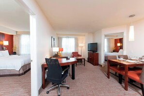 A hotel room with a bed, a desk with a chair, a television, and a dining area with a table and chairs. - Residence Inn Marriott Moline (Moline)