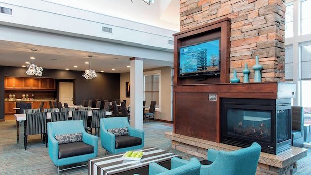 A spacious lobby with a fireplace, comfortable seating, and a television screen. - Residence Inn Marriott Moline (Moline)