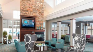 A spacious lobby with a stone fireplace, comfortable seating, and a large flat-screen TV. - Residence Inn Marriott Moline (Moline)