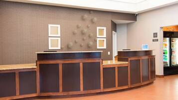 A reception desk with a brown wall, framed pictures, and a small sign.