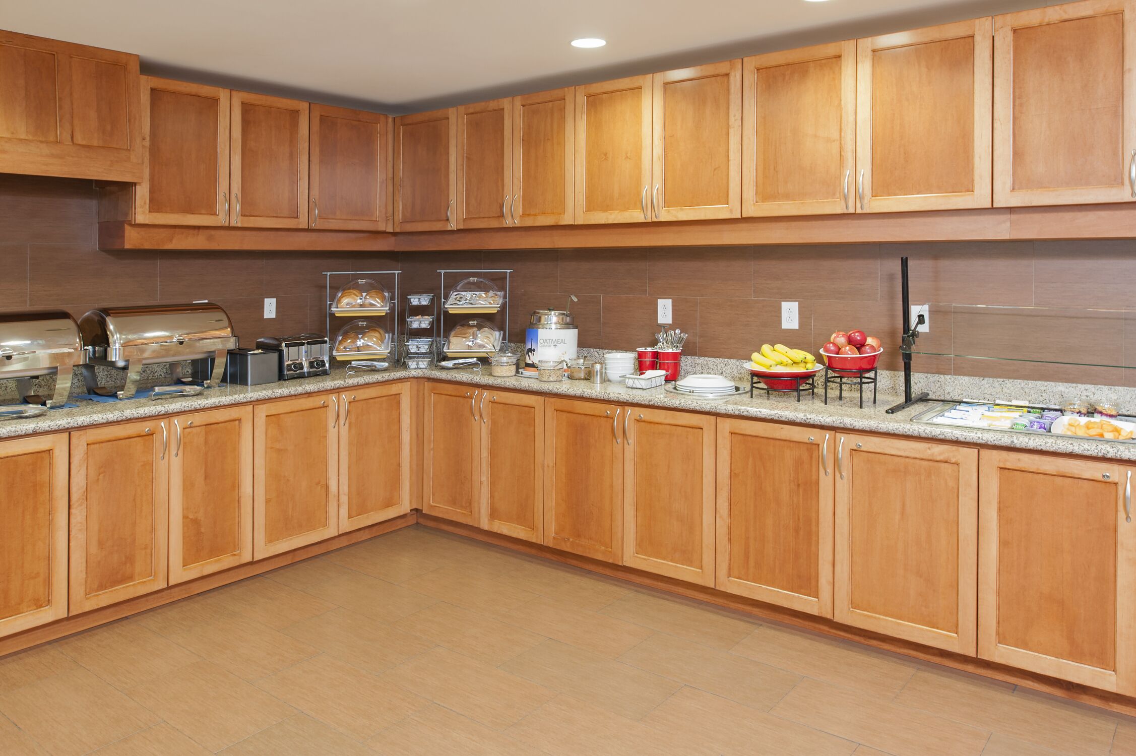A kitchen with wooden cabinets, granite countertops, and various appliances including a coffee maker and a toaster.