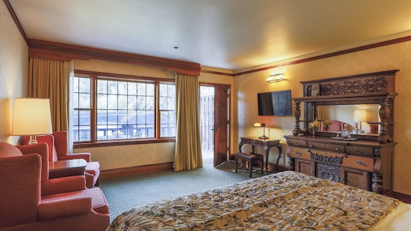 A hotel room with a bed, a desk, a chair, a dresser, and a large window with curtains.