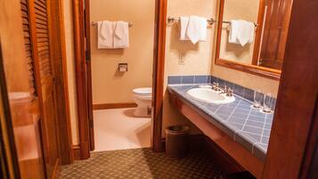 A bathroom with a toilet, sink, and mirror.