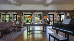 A grand room with a piano, a globe, and a bench.